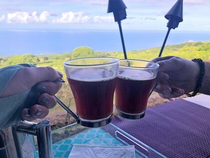 A close-up shot of clinking coffee mugs at Kona Joe Coffee farm on the Big Island.