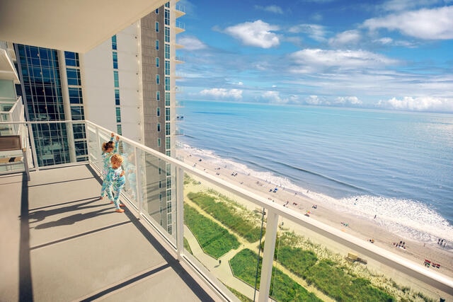 Young girls in pajamas looking out to sea on a Hilton Grand Vacations Myrtle Beach resort private balcony. 