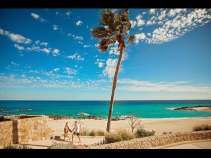 Couple walking along walkway with beach in the distance while on vacation, La Pacifica Los Cabos by Hilton Club.