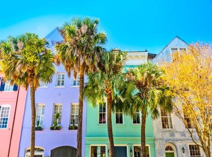 Four pastel-painted buildings and palm trees along Rainbow Row in Charleston, South Carolina