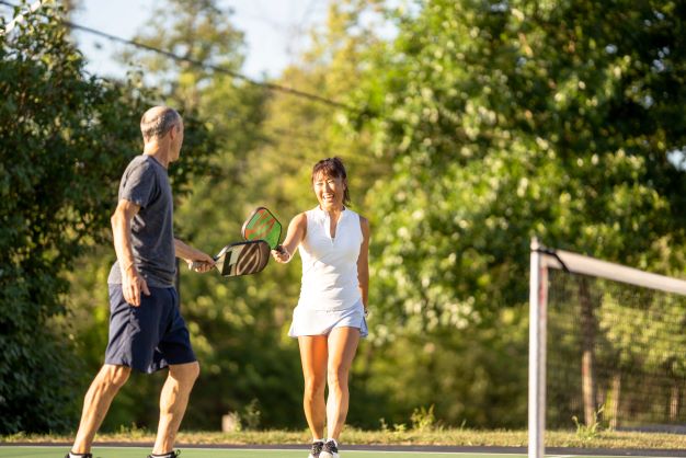 Couple happily playing pickleball outdoors.