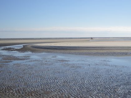 Two people in the distance walk on the beach of St. Simons Island, Georgia