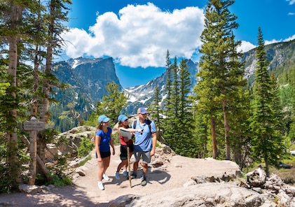 A family of three happily hikes a mountain trail in Estes Park, Rocky Mountains National Park, Colorado