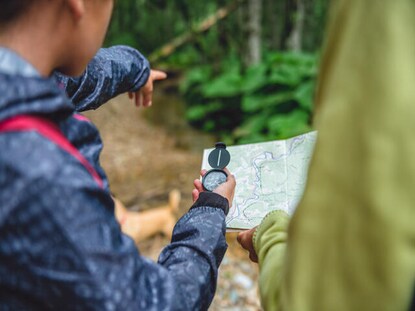 People exploring the outdoors with a map and compass. 