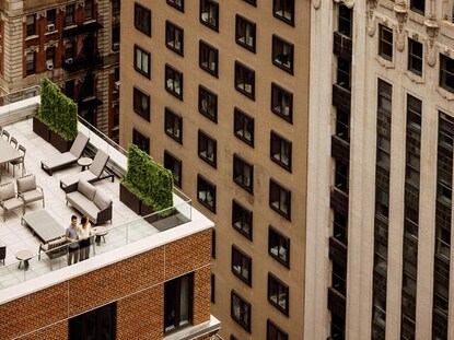 Couple looking down on the city below from rooftop terrace at The Quin by Hilton Club in New York City. 