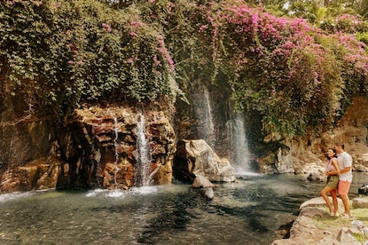 Couple embracing while enjoying the view of a waterfall in Maui, Hawaii. 